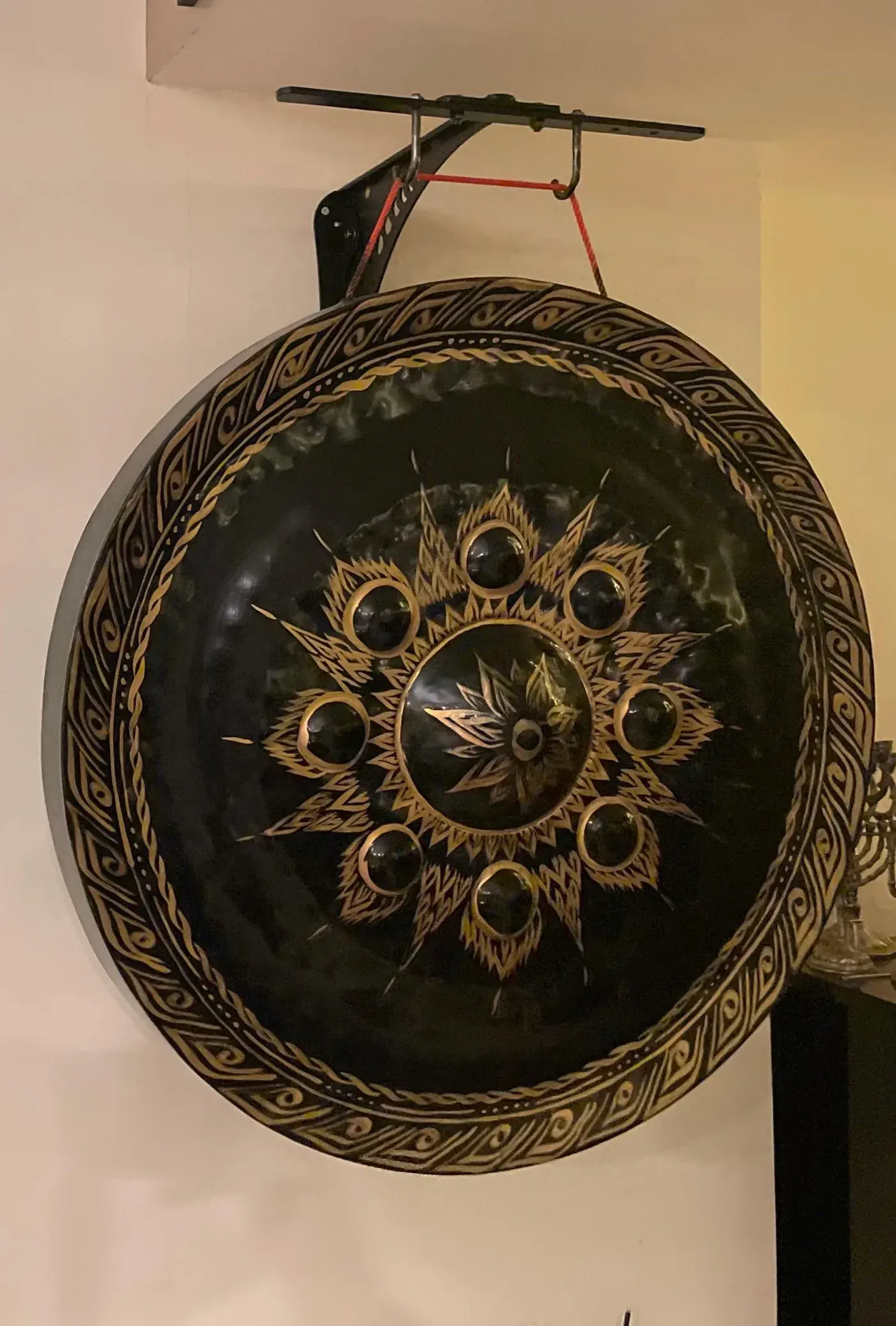 Hand-hammered black and gold gong mounted on a wall bracket in a New York apartment